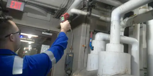 Field engineer taking measurements on industrial pipework